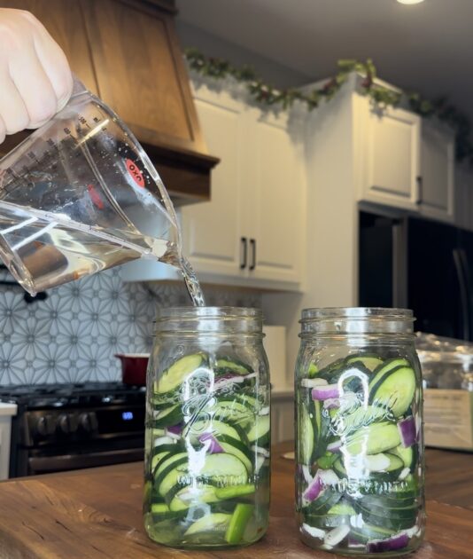 Pouring liquid into cucumber salad mason jars